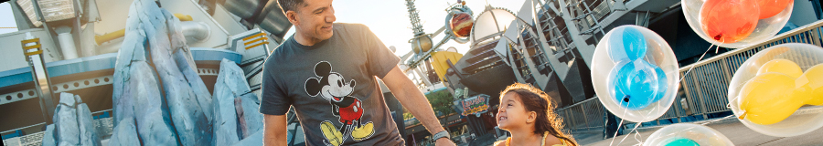 A little girl and her dad holding hands while walking through Tomorrowland at Magic Kingdom park A little girl and her dad holding hands while walking through Tomorrowland at Magic Kingdom park