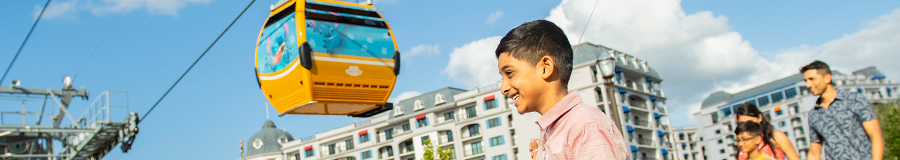 A father and son stroll beneath a Disney Skyliner gondola A father and son stroll beneath a Disney Skyliner gondola